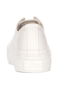 Białe płócienne sneakersy o teksturowanej powierzchni, grubej białej podeszwie i widocznym logo na pięcie. Zaokrąglony kształt i brak zdobień.