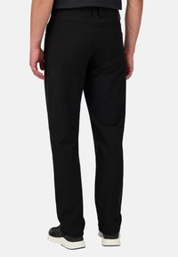 Pantalones negros de tela suave, con un diseño de pierna recta, bolsillos traseros cosidos y combinados con zapatillas negras.