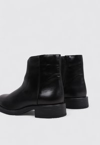 Black leather ankle boots with a smooth texture, low block heels, and a zip closure at the back. Rounded toe design.