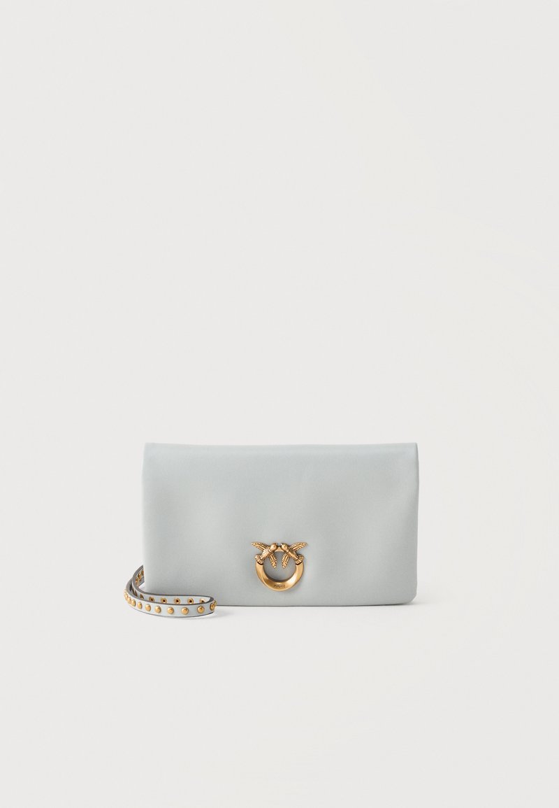 Φωτεινή γκρι δερμάτινη τσάντα χειρός με χρυσό κούμπωμα σε σχήμα πουλιού και ταιριαστή λουρίδα καρπού διακοσμημένη με χρυσά καρφιά, σε απλό φόντο.