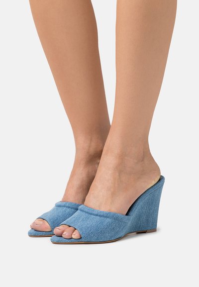 Sandale cu toc wedge din denim albastru, cu design cu vârf deschis și spate acoperit. Prezintă o textură moale a materialului și un toc wedge conturat.