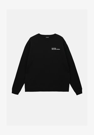 Svart hettegenser med rund hals, ribbestrikkede mansjetter og teksten "DIN TUR, TA EN PLASS & SLAPP AV" i hvit brodering på brystet.