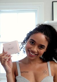 Rosa Box mit der Aufschrift "Ionic Shot", die in einer Hand gehalten wird. Das Produkt hat ein einfaches, sauberes Design mit sanften Ecken und minimalem Text.