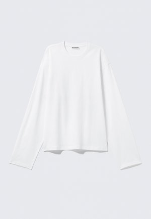 Hvit langermet t-skjorte med avslappet passform. Laget av mykt bomullsstoff, har rund hals og senkede skuldre. Rent design.