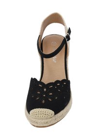 Espadrille en tissu noir avec un design floral découpé et un capuchon en crochet beige. Présente une sangle avec boucle ajustable. Semelle en jute.