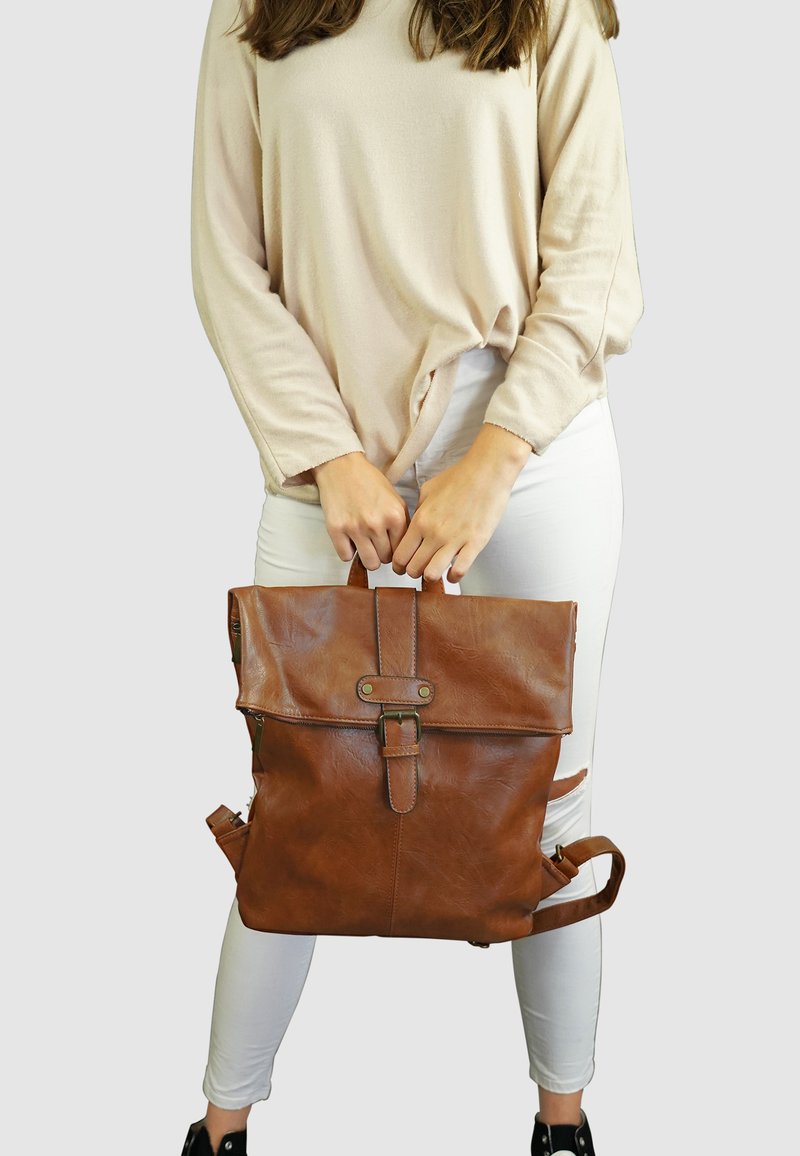 Bruine leren rugzak met een rol-top ontwerp, een voorklip met een gesp, zijvakken en verstelbare schouderbanden.