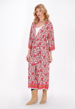 Kimono a stampa floreale con accenti rosa e verdi, maniche lunghe e una cintura in vita. Indossato sopra una maglietta bianca e abbinato a stivali beige.