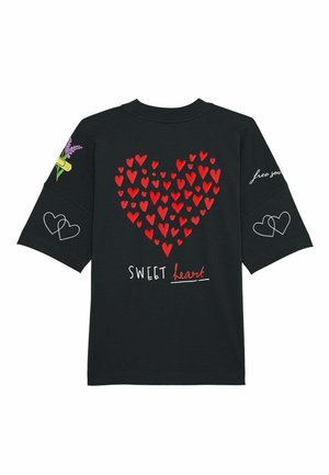 Melna kokvilnas t-krekls ar lielu sarkanu sirds grafiku, kas izgatavota no mazākām sirdīm, uzrakstu "SWEET heart" un ziedu akcentiem uz piedurknēm.
