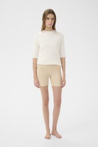 Fehér bordázott felső rövid ujjakkal, hullámos széllel és bézs rövidnadrággal. Simább textúra, testhezálló fazon és semleges színek.