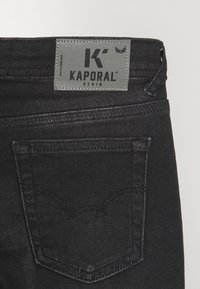 Zwarte spijkerbroek van denim met een Kaporal-label op de tailleband, voorzien van opvallende stiksels en een achterzak met een gebogen ontwerp.