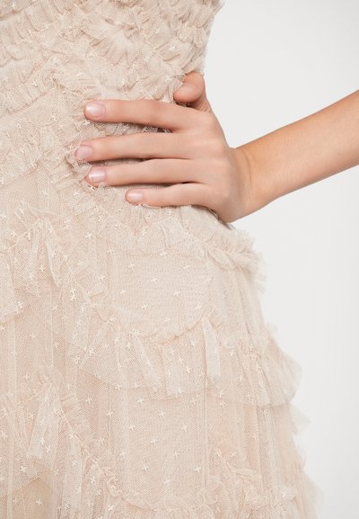 Ροζ φόρεμα με ριγέ στρώσεις και υφή με κουκίδες. Κοντινό πλάνο χεριού που ακουμπάει στο ύφασμα, αναδεικνύοντας την απαλότητα και τις λεπτομέρειες.