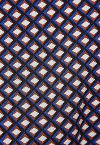 Wzór geometryczny z powtarzającymi się diamentowymi kształtami w kolorach brązowym, niebieskim, czarnym i białym na tkaninie.