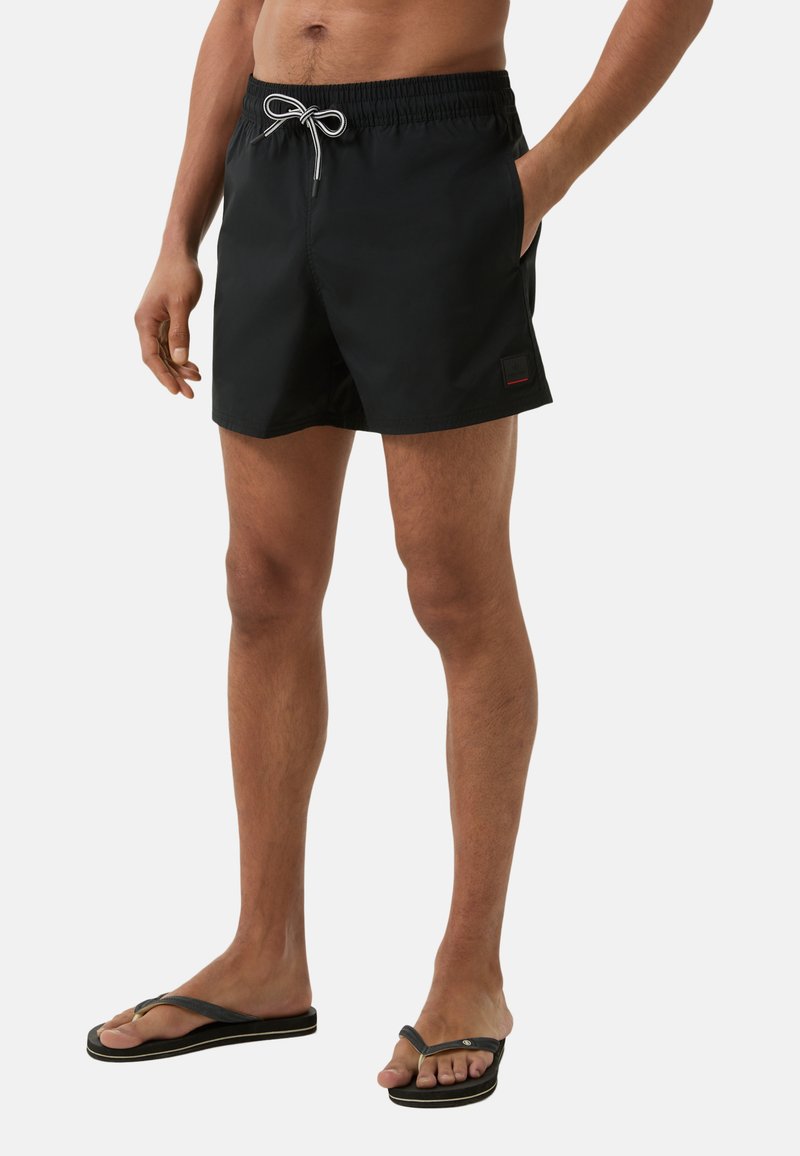 Shorts de bain noirs en tissu léger, avec une taille élastique dotée d'un cordon de serrage, des poches latérales et un petit patch logo.