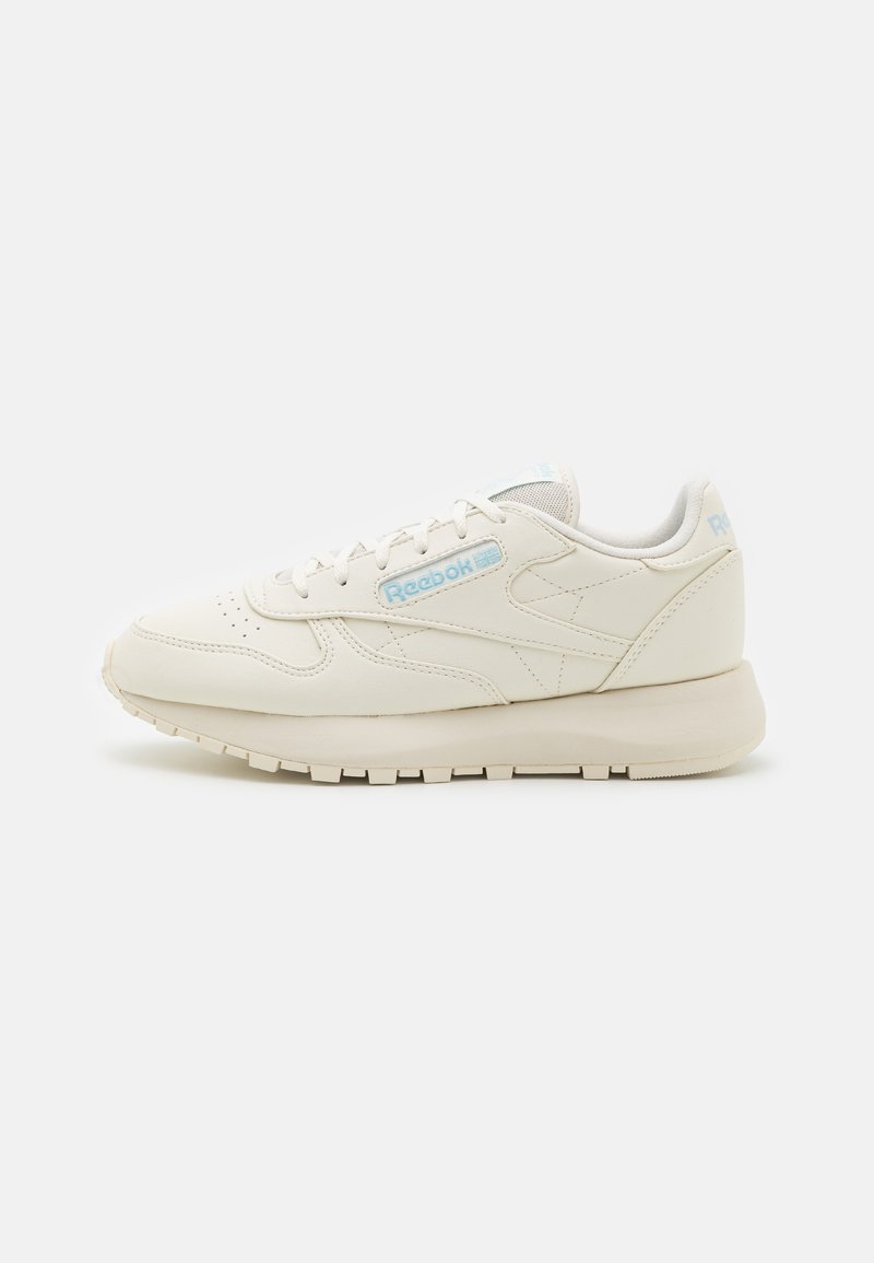 Reebok sneakers in off-white leather, featuring a textured upper, light blue logo, lace-up closure, and a cushioned sole for comfort.