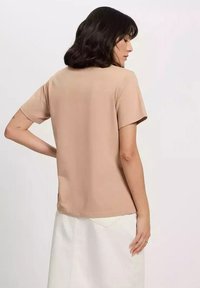 T-shirt z krótkim rękawem, wykonany z miękkiego materiału w beżowym kolorze, o luźnym kroju i prostym wzorze, z prostym dołem oraz minimalnymi detalami w szwach.