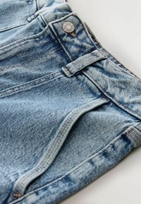 Világoskék farmer rövidnadrág, halovány textúrával, gombos záródással és övhurkokkal, a szélén varrási részletekkel.