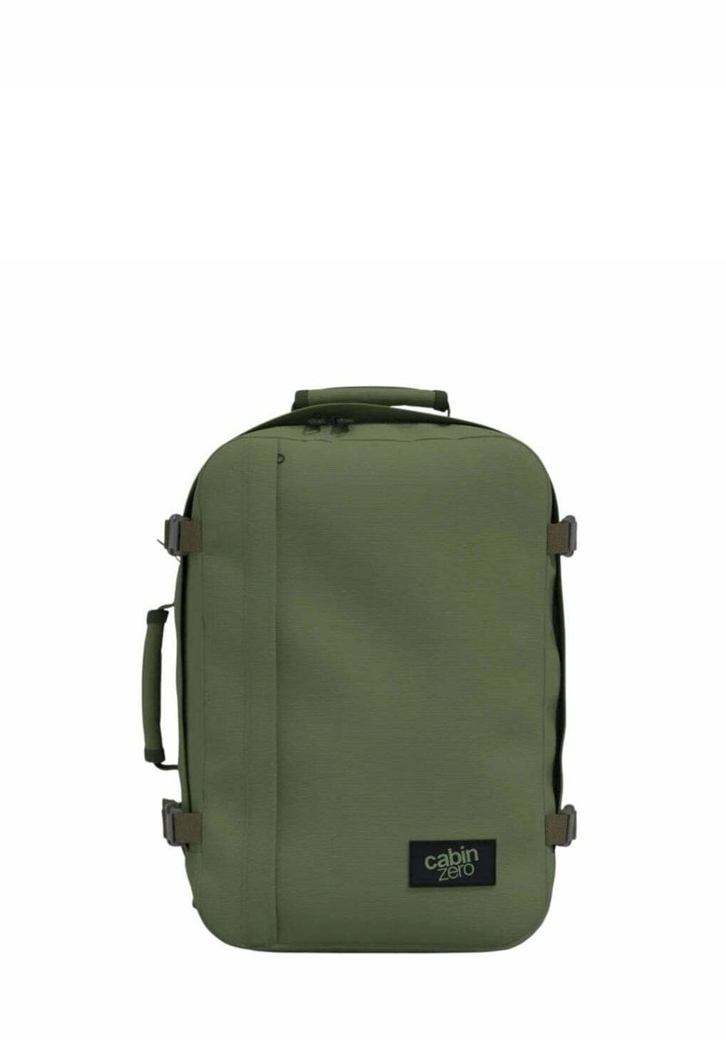 Vihreä kangaskassi suorakulmaisen muodon kanssa, kylkiläisillä kahvoilla, säädettävillä hihnoilla ja logopatchilla. Rakenteellinen materiaali vetoketjuilla.