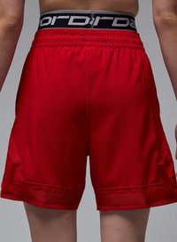 Røde atletikshorts med en elastisk sort talje, der har hvid skrift. Glat stof med sidepaneler og en pæn kantfinish.