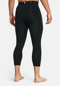 Schwarze Sportleggings mit einer figurbetonten Passform, elastischem Bund und seitlichen Taschen. Das Material wirkt glatt und dehnbar, geeignet für aktive Kleidung.