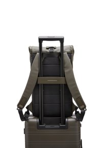 Sac à dos en tissu vert, bordé de noir, attaché à une valise rigide noire. Comprend des bretelles ajustables et une poignée télescopique.