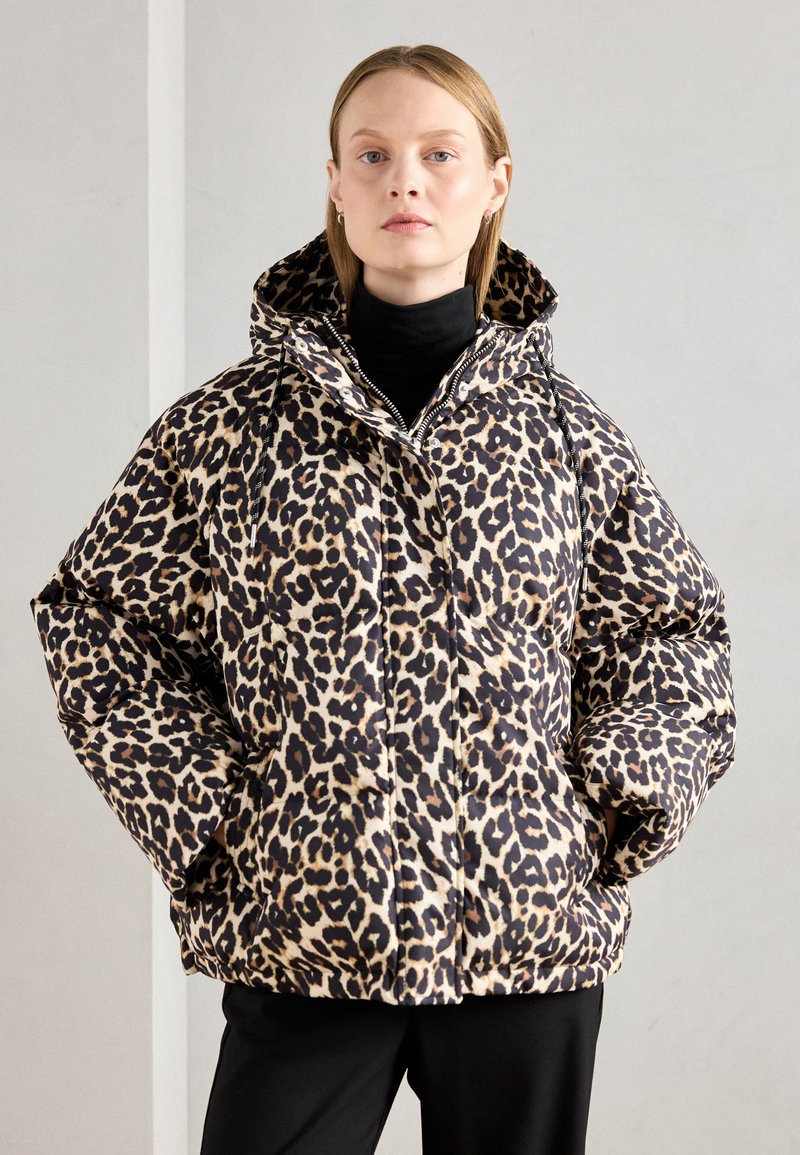 Chamarra tipo puff en estampado de leopardo con capucha, que presenta un diseño grueso y acolchado en tonos beige y negro. Detalles de cremallera y bolsillos laterales.