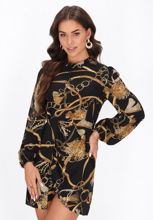 Schwarzes Kleid mit goldener Kette und Blumenmuster, hohem Ausschnitt, langen Ärmeln und Wickeldesign. Glatter Stoff mit leichtem Glanz.