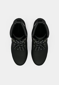 Botas pretas de tornozelo com textura suave, apresentando atacadores com padrão preto e branco, ferragens douradas e design de biqueira arredondada.