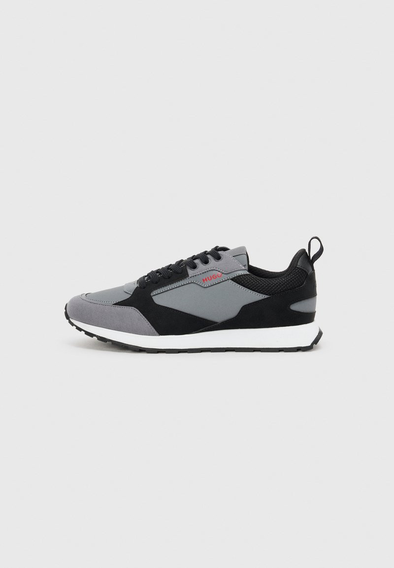 Grå og svart atletisk sneakers med overdel i mesh og semsket skinn, hvit mellomsåle, svart gummisåle og en rød logoakse.
