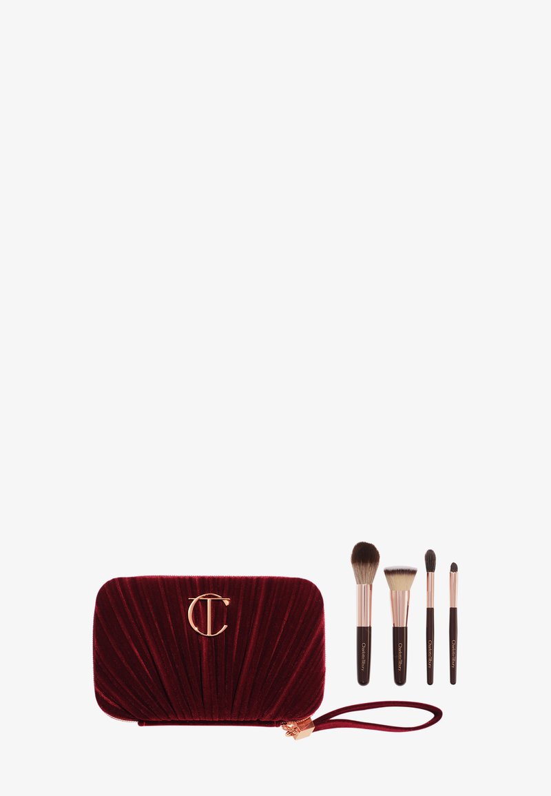 Samtige burgunderfarbene Kosmetiktasche mit gefälteltem Design und goldenem Logo, begleitet von vier Make-up-Pinseln mit schwarzen Griffen und weichen Borsten.