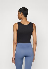 Black sleeveless top with a round neckline, paired with ribbed blue leggings. The fabric appears stretchy and form-fitting.