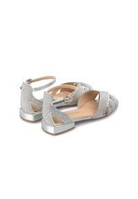 Zilveren platte schoenen met uitgesneden ontwerp, versierd met strass-steentjes, spitse neus, enkelband en een lage blokhak. Glad textuur.