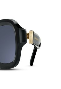 Occhiali da sole neri oversize con una montatura spessa, cerniera con dettagli dorati e lenti scure. Accenti testurizzati sui lati aggiungono chic.