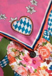 Mehrfarbiger Seidenschal mit Blumenmustern, einem pinkfarbenen Hintergrund, blauen und weißen diamondförmigen Herzen sowie einem orangen Saum mit einem schwarzen Logoschild.