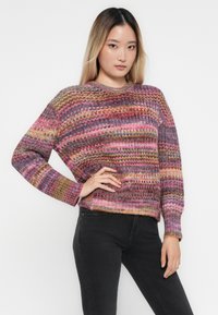 Pull en tricot multicolore avec des rayures horizontales dans des nuances de rose, violet et or. Coupe ample avec des poignets et un ourlet côtelés.