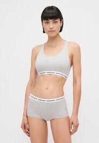 Grijze katoenen sport-bh en boxershorts van effen stof met een contrasterende witte tailleband waarop "BJÖRN BORG" is afgebeeld.