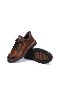 Chaussures en cuir marron avec un bout arrondi, un design à lacets, un détail de zip et une semelle en caoutchouc texturée avec un motif pour l'accroche.