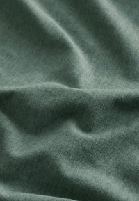 Tissu doux vert clair avec de subtils plis et une texture fine en tricot, montrant des plis délicats et des détails de surface lisses.