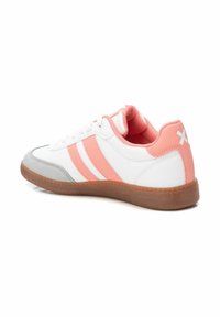 Zapatilla blanca con acentos rosa y dos franjas horizontales. Presenta una puntera gris y una suela marrón texturizada. Cuello acolchado suave.