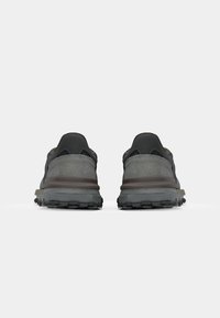 Grijze buitenschoenen met een gestructureerde suede en mesh bovenkant, donkere accenten en robuuste zolen die zijn ontworpen voor grip. De achteraanzicht toont de details van de padding.