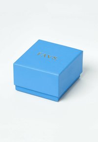 Blå fyrkantig smyckeslåda med guldtexten "FAVS." på locket, placerad på en vit yta.