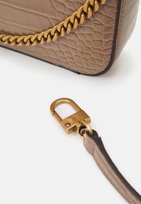 Beige læder håndtaske med en struktureret overflade, der har en guld kæderekke og en metal lukning på siden.