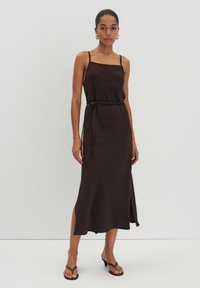 Braunes ärmelloses Kleid mit geradem Schnitt, seitlichem Schlitz und dünnen Trägern. Ausgestattet mit einem dünnen schwarzen Gürtel in der Taille. Hergestellt aus glattem Stoff.