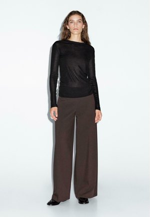 Black long-sleeve top paired with high-waisted, wide-leg brown trousers. Smooth, lightweight fabric with a fitted silhouette.