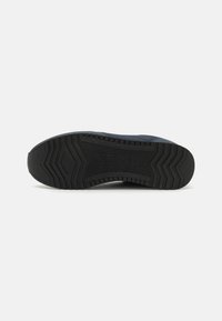 Svart gummisåle til sneakers med teksturert gripemønster og hexagonale former. Holdbart materiale med en lett hevet hæl for bedre feste.