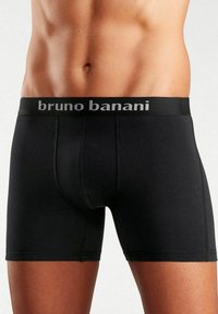 Melni bokseršorti no bruno banani, ar mīkstu jostu un pelēku logo, gludu tekstūru un pieguļošu dizainu.