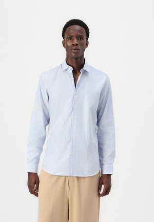 Lyseblå og hvid stribet skjorte med knaplukning, krave, lange ærmer og en glat stofstruktur. Har en lige kant og standard knapper.