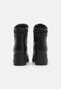 Black leather ankle boots with a textured upper, a padded collar, and block heels. Features a wire accent at the ankle.