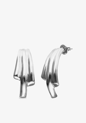 Boucles d'oreilles clous en métal argenté incurvé avec un design sculptural plié et une finition polie, présentées sous des angles de face et de côté.