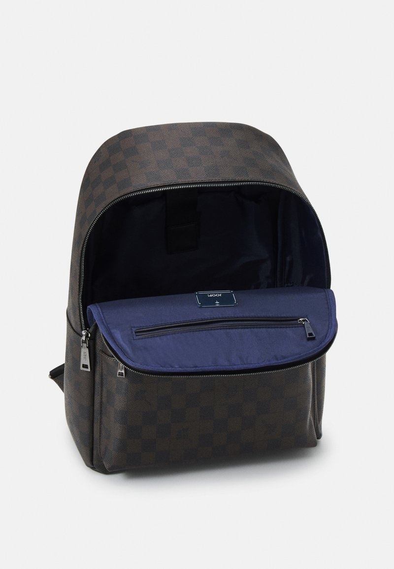 Braun karierter Stoff-Rucksack mit einem gepolsterten marineblauen Innenraum und einer vorderen Tasche, ausgestattet mit einem Klappenverschluss und verstellbaren Trägern.