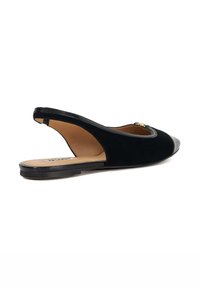 Black slip-on slingback shoe featuring a rounded toe, suede upper, patent leather cap toe, and a low, flat heel.